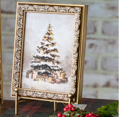 Ornate gold picture frame with baroque-style scrollwork borders, each displaying a winter Christmas tree scene with wrapped gifts. The frame is shown standing open on a gold stand.