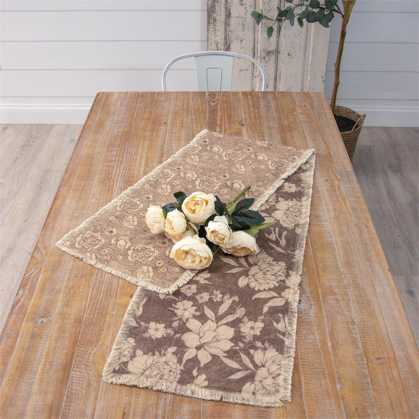 Reversible table runner floral-patterned table runner on a wooden table with white flowers.