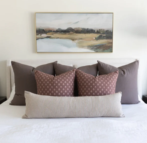 Bed with decorative pillows and a painting on the wall