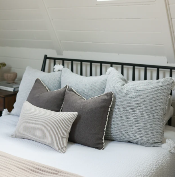 Decorative pillows on a bed with a neutral color palette.