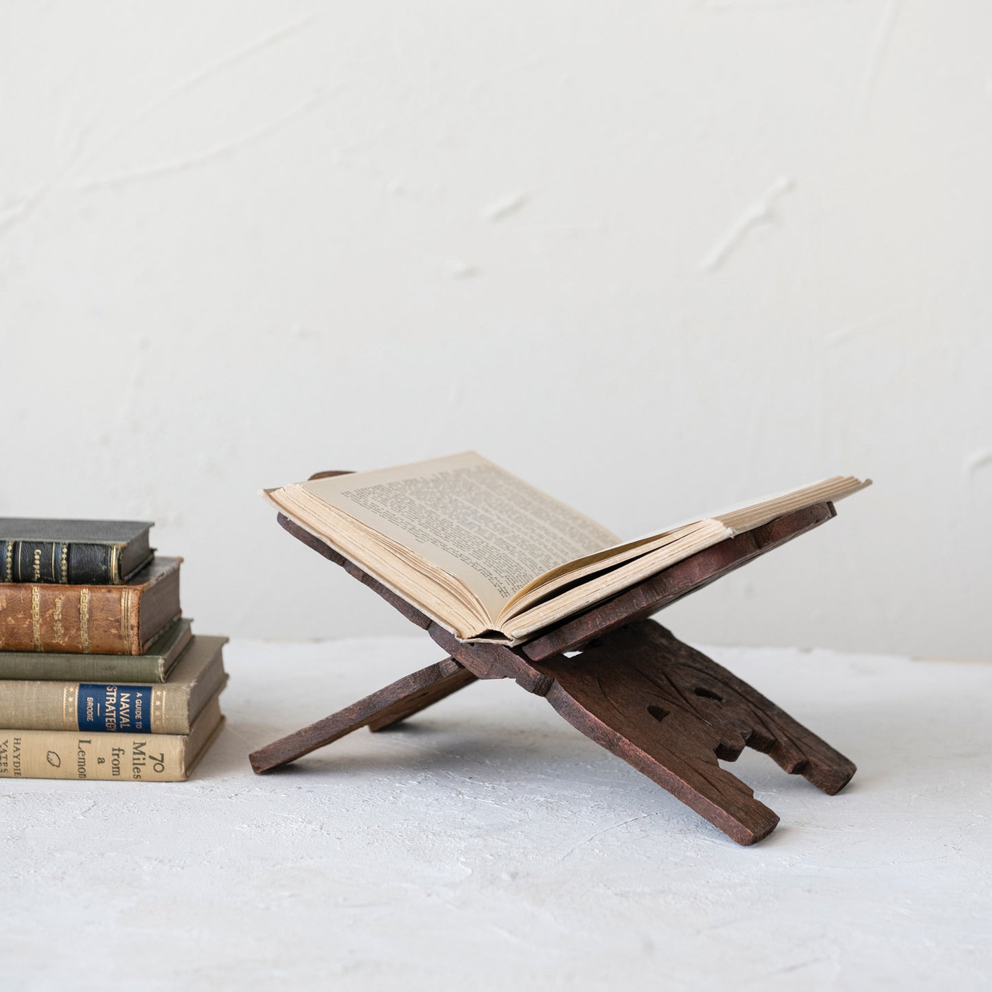 A beautiful wooden cookbook stand with an open book on a white surface