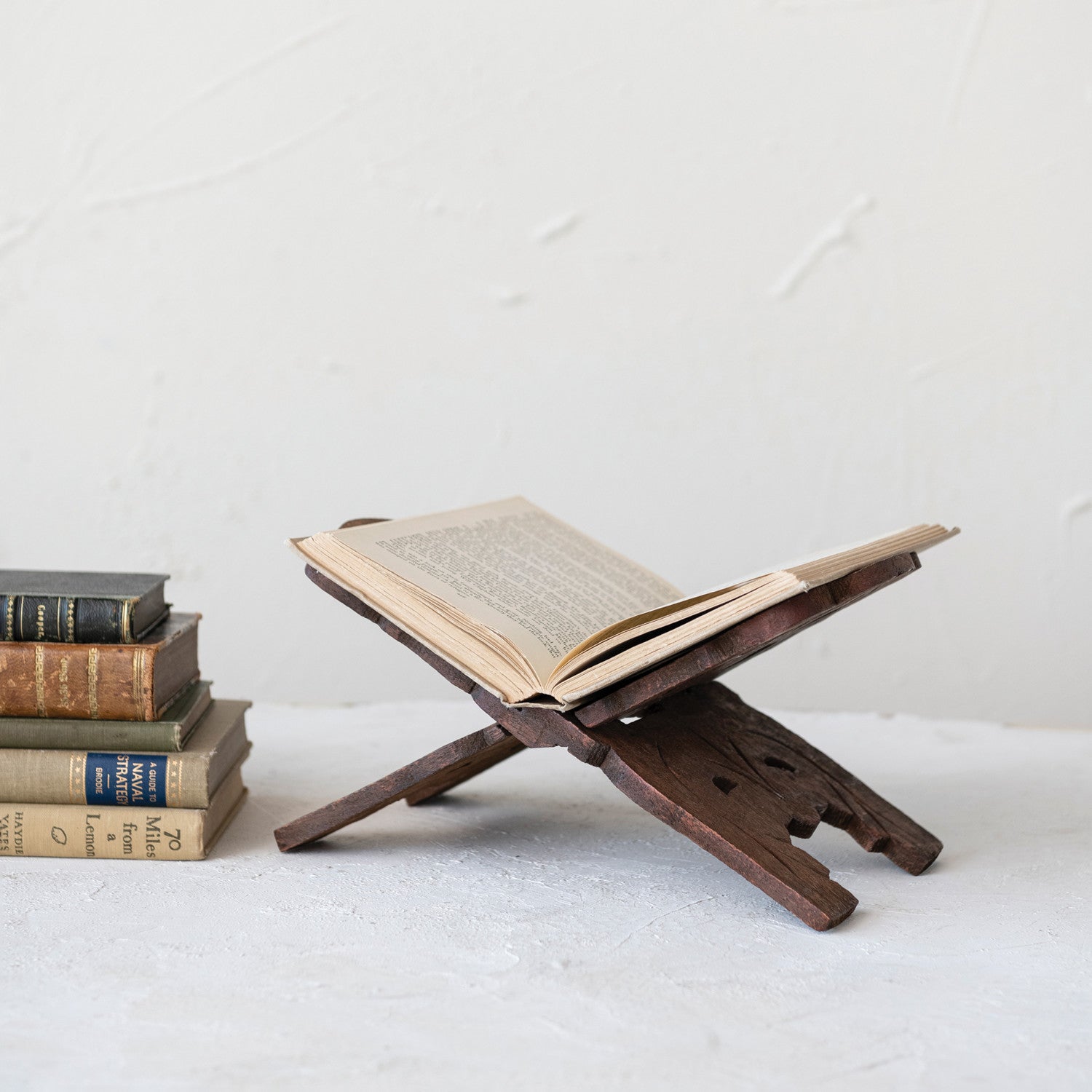 A beautiful wooden cookbook stand with an open book on a white surface