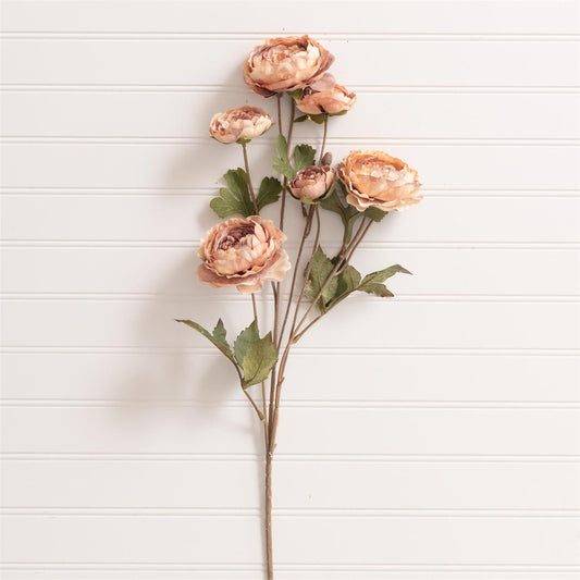 Artificial flower stem with peach-colored flowers on a white wooden background