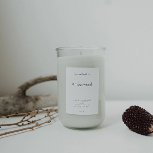 Candle labeled 'Amberwood' with natural elements on a light background