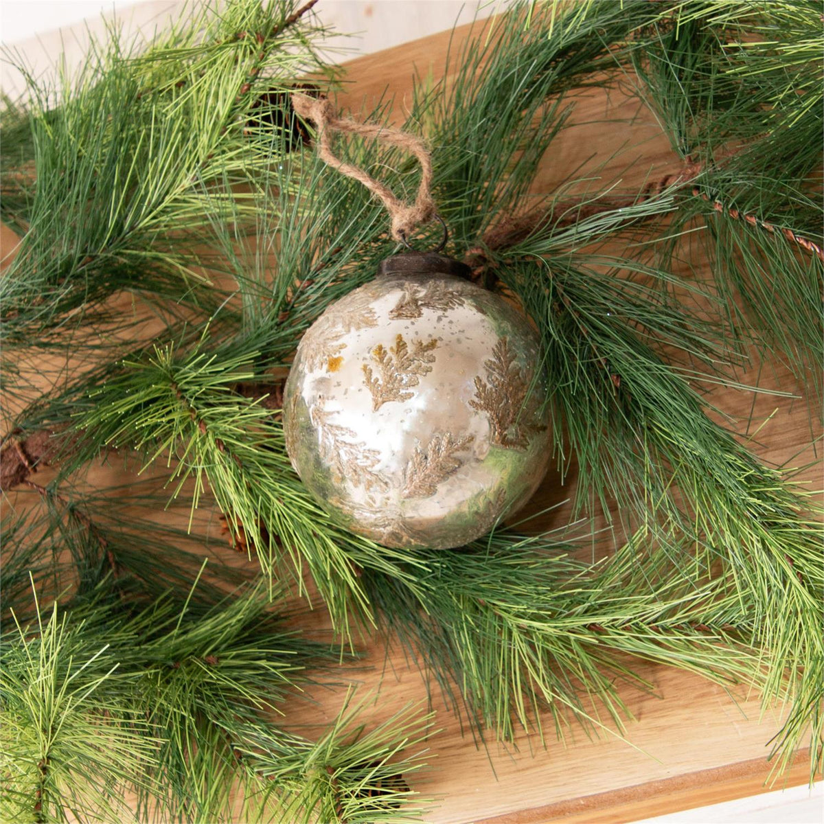 Decorative ornament on a bed of green pine needles with a wooden surface underneath
