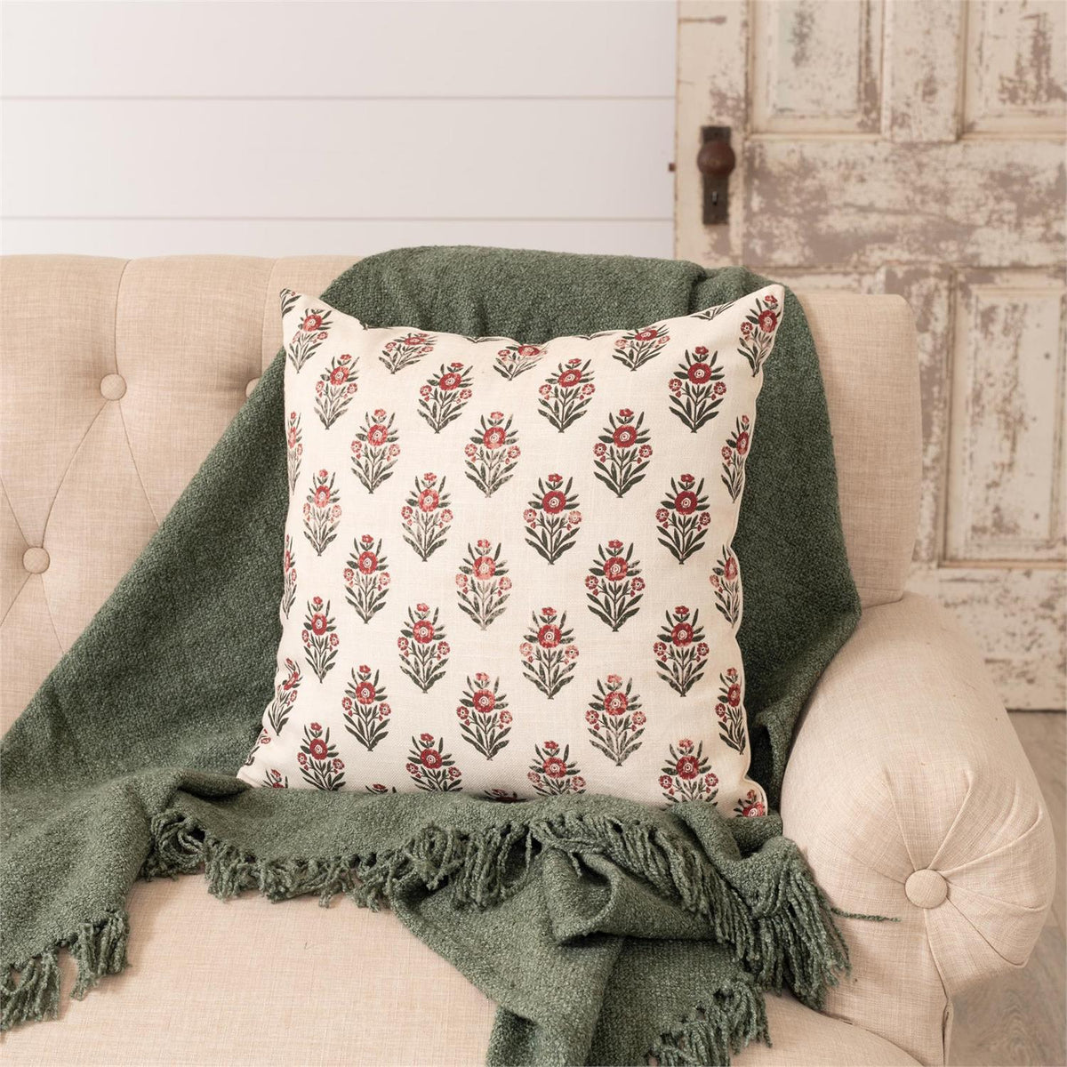 Decorative pillow with floral pattern on a beige sofa with a green blanket