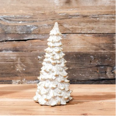 Decorative white Christmas tree on a wooden surface with a rustic wooden wall background.