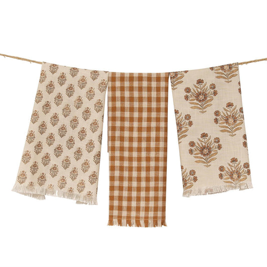 Fall Tea towels with floral and checkered patterns hanging on a line.