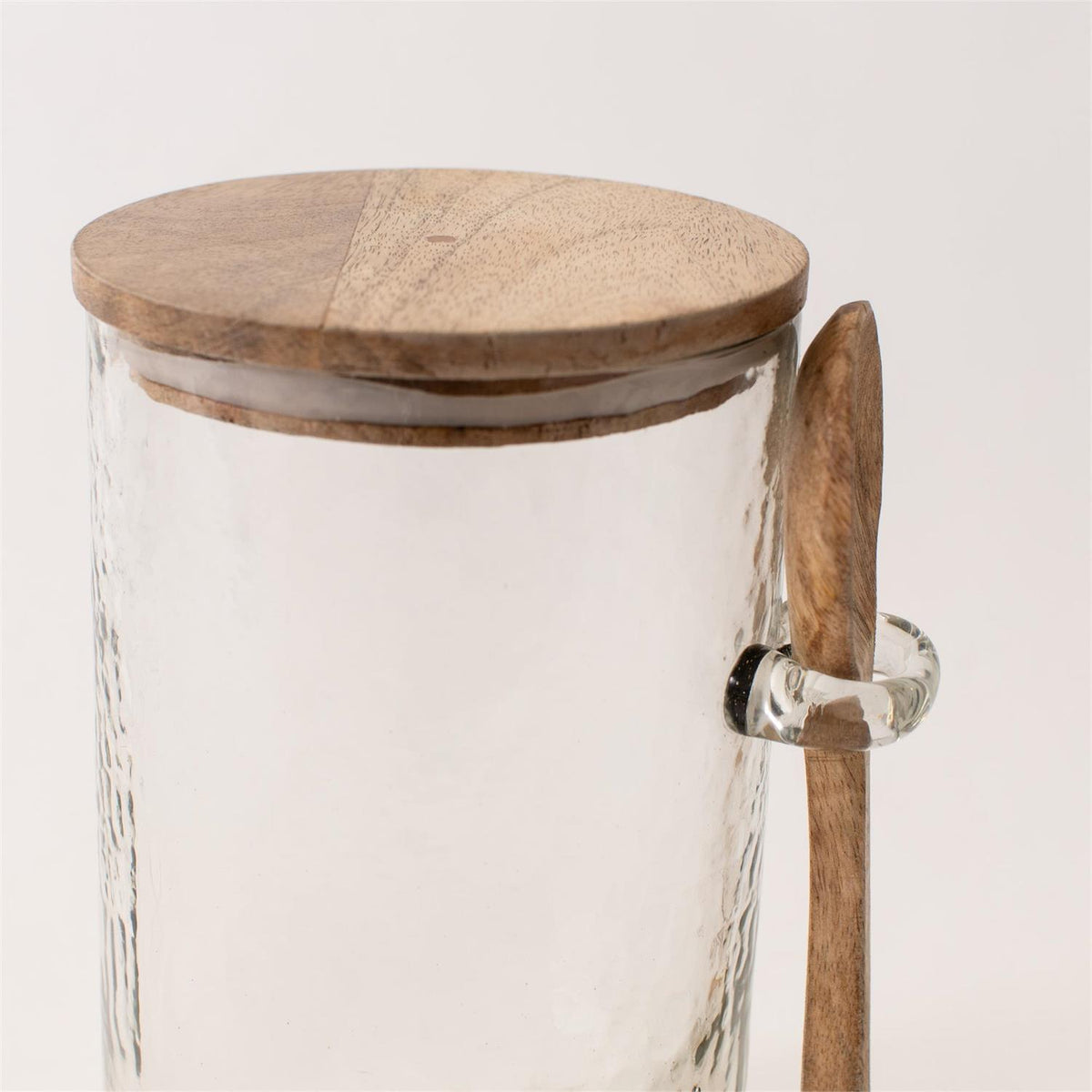 Glass jar with wooden lid and spoon on a light background