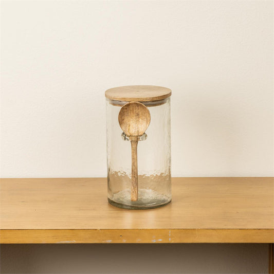 Glass jar with wooden lid and handle on a wooden surface