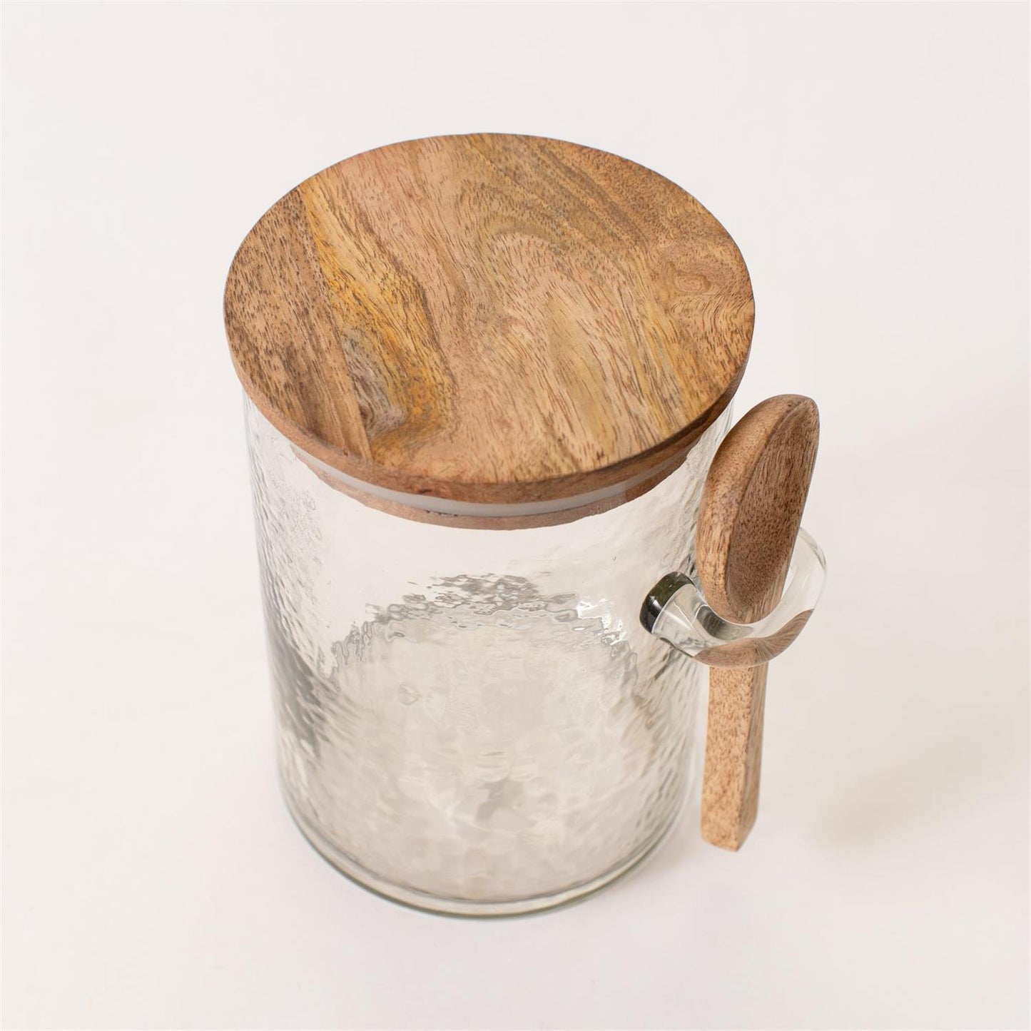 Glass jar with wooden lid and spoon on a white background