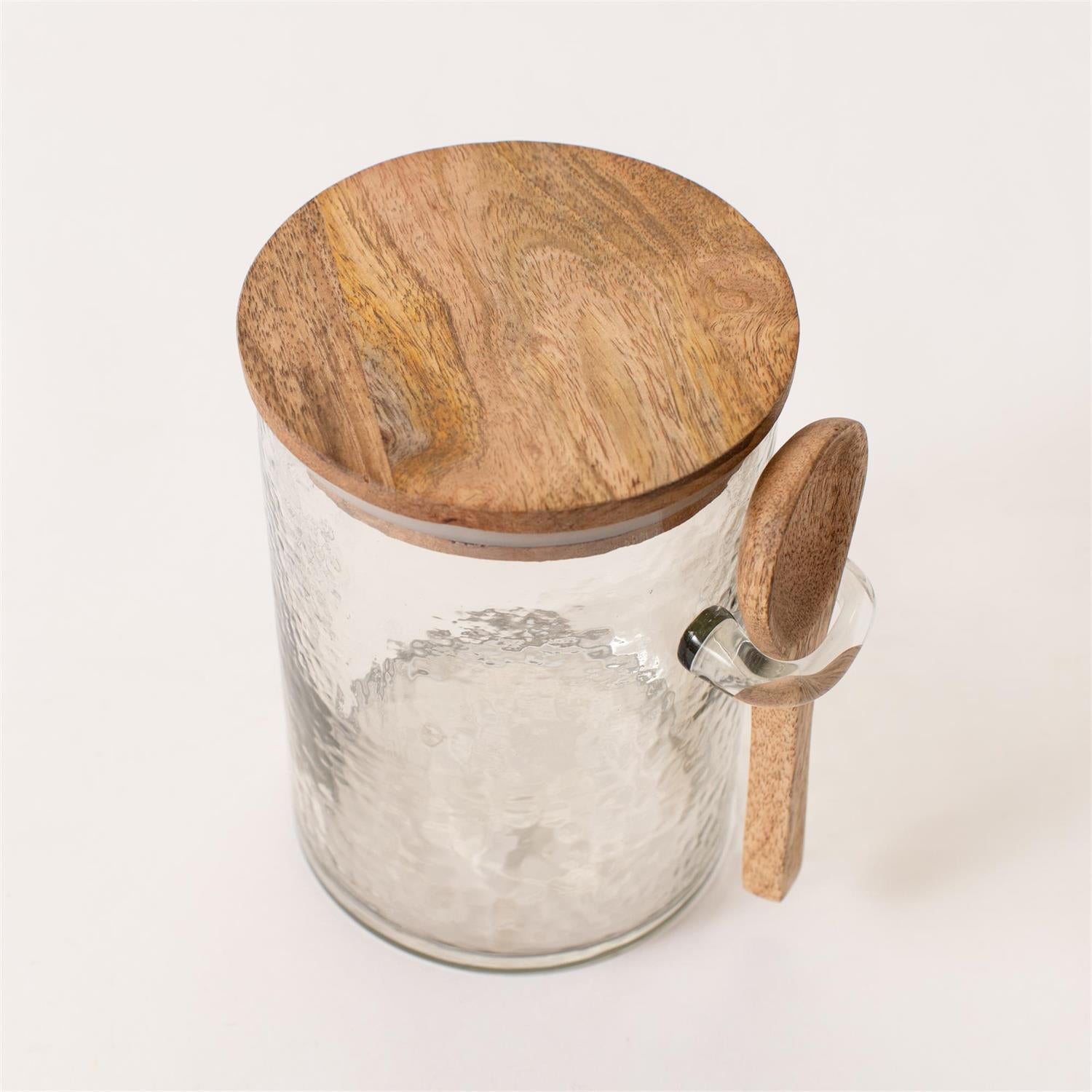 Glass jar with wooden lid and spoon on a white background