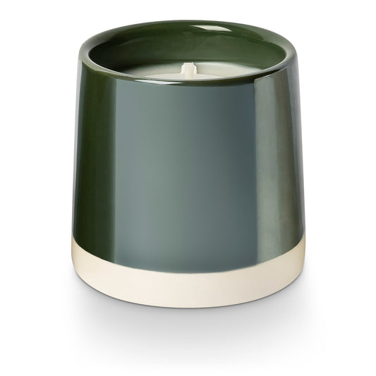 Green candle holder with a candle inside on a white background
