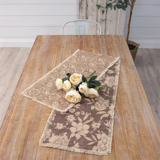 Reversible table runner floral-patterned table runner on a wooden table with white flowers.