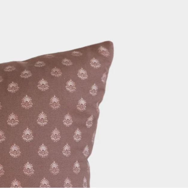 Brown pillow with white floral pattern on a light gray background