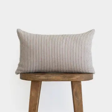 Striped pillow on a wooden stool against a white background