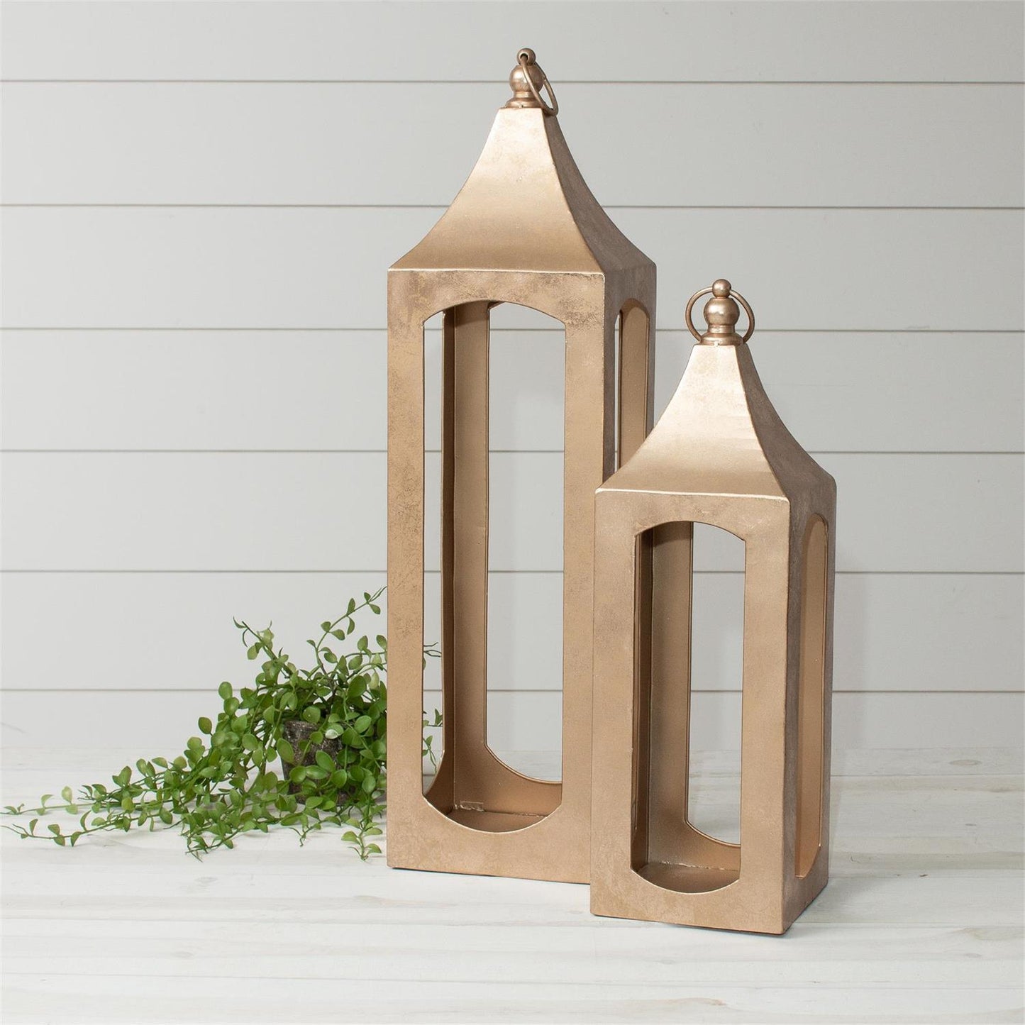 Two wooden lanterns with metallic tops on a light wooden floor.