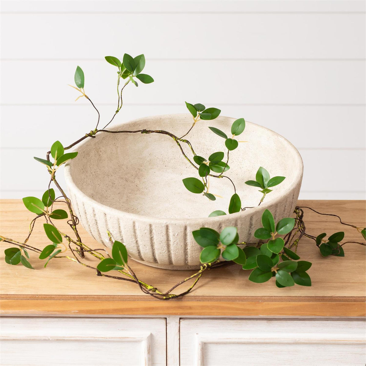 White ceramic bowl with green leaves on a wooden surface