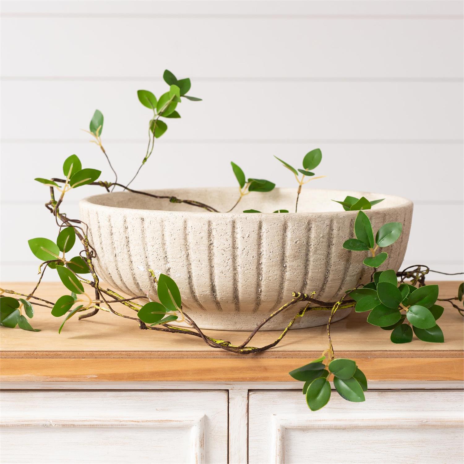 White ceramic stripped bowl with green leaves on a wooden surface