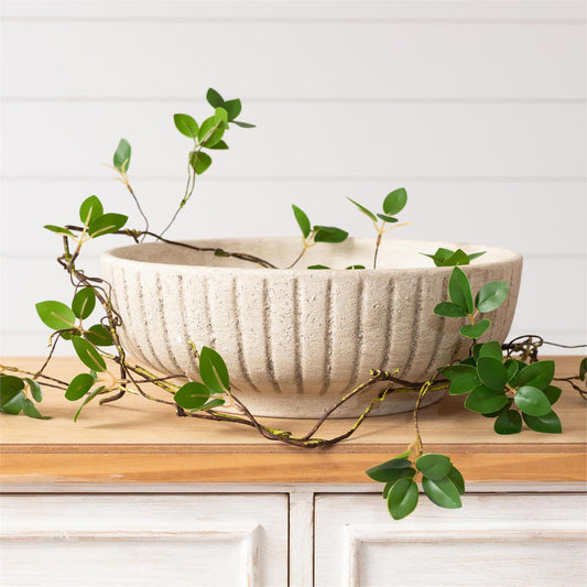 White ceramic stripped bowl with green leaves on a wooden surface