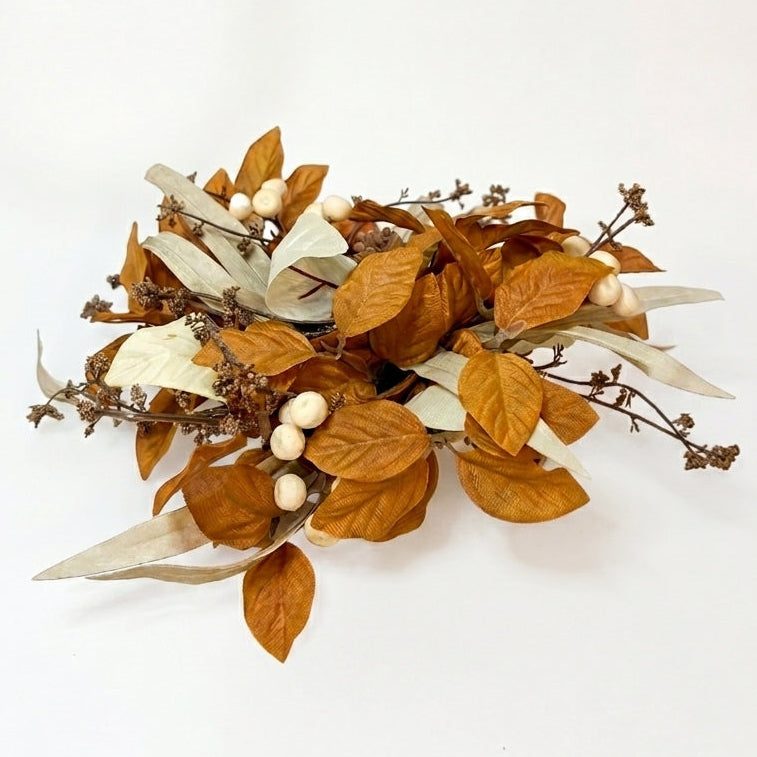 An autumn-themed artificial floral wreath featuring warm brown leaves, pale cream leaves, and small cream berries on a white background.