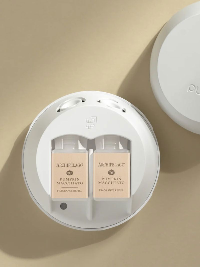 Two Archipelago perfume bottles in a white container on a beige background