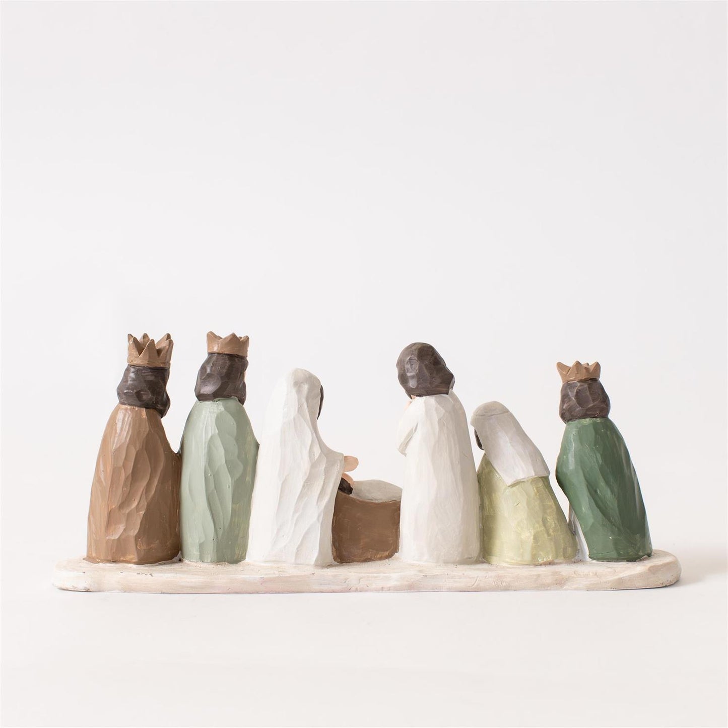 A small figurine set depicting the Three Wise Men and the baby Jesus on a base, photographed against a plain white background.