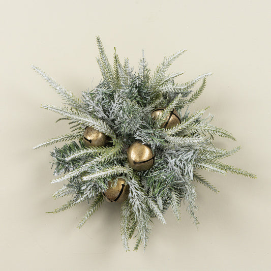 A frosted pine branch wreath with five small gold bells, photographed against a solid light beige background.