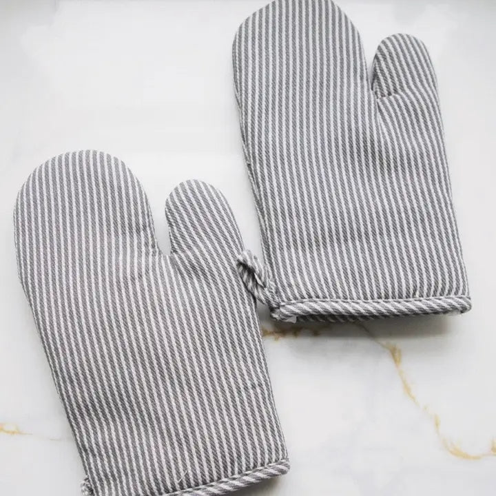 Pair of gray and white striped oven mitts on a marble surface