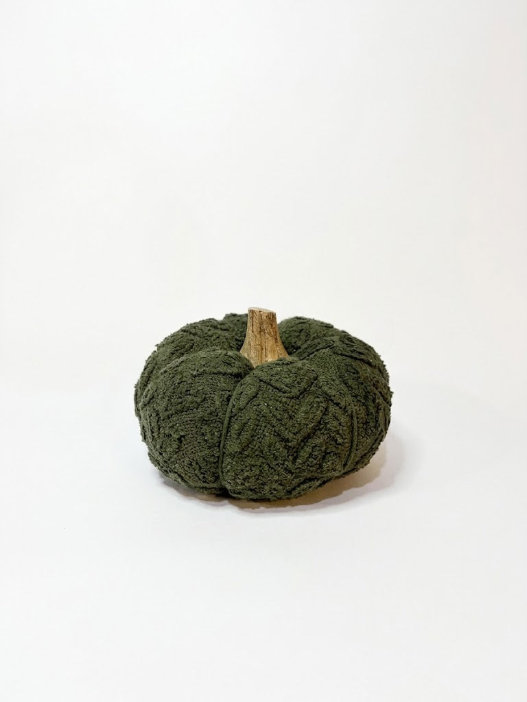 A small decorative pumpkin made from dark olive green textured yarn with a natural brown stem, photographed on a clean white background.