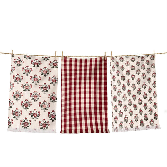 Three towels with floral and checkered patterns hanging on a line.